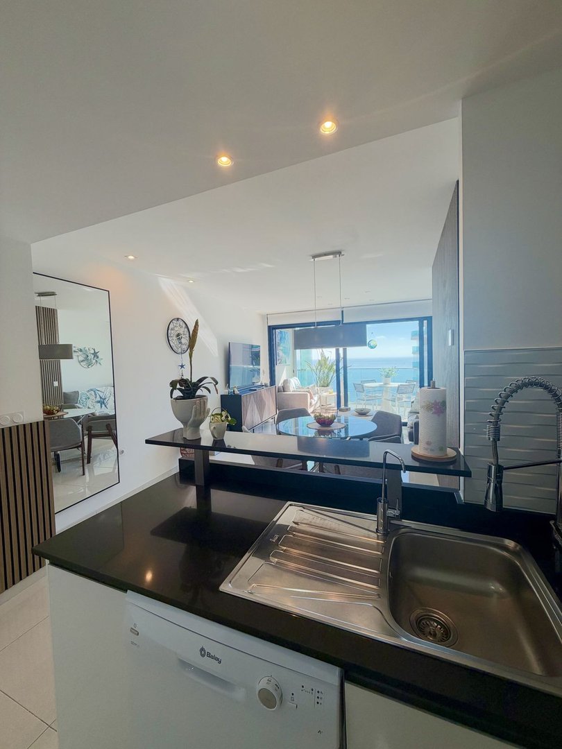 Modern open-plan kitchen and dining area with a large window offering a stunning sea view.