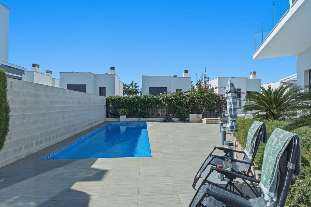 Modern villa with a swimming pool and patio area with lounge chairs