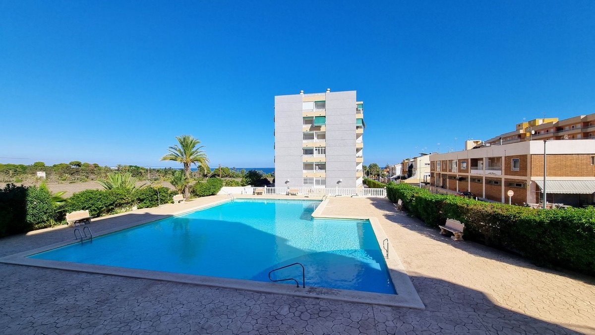 Apartment complex with swimming pool, palm trees, and ocean view
