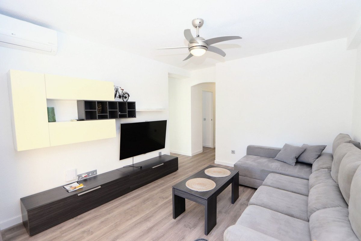 Modern living room with grey sofa, flat-screen TV, and wooden flooring.