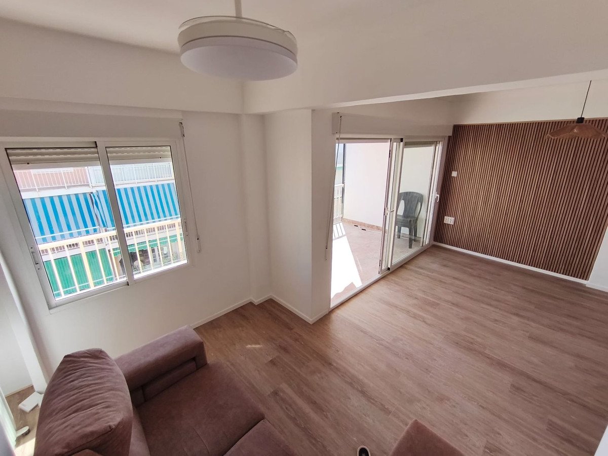 Modern living room with wooden accent wall, large sliding glass doors leading to a balcony, and a sofa.