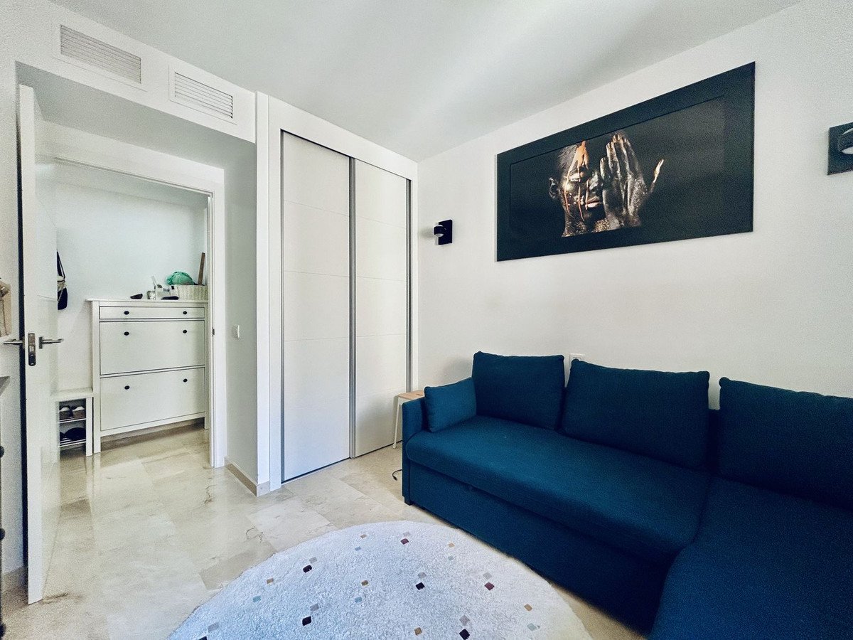 Modern living room with a blue sectional sofa, abstract art on the wall, and a hallway entrance with storage cabinets.