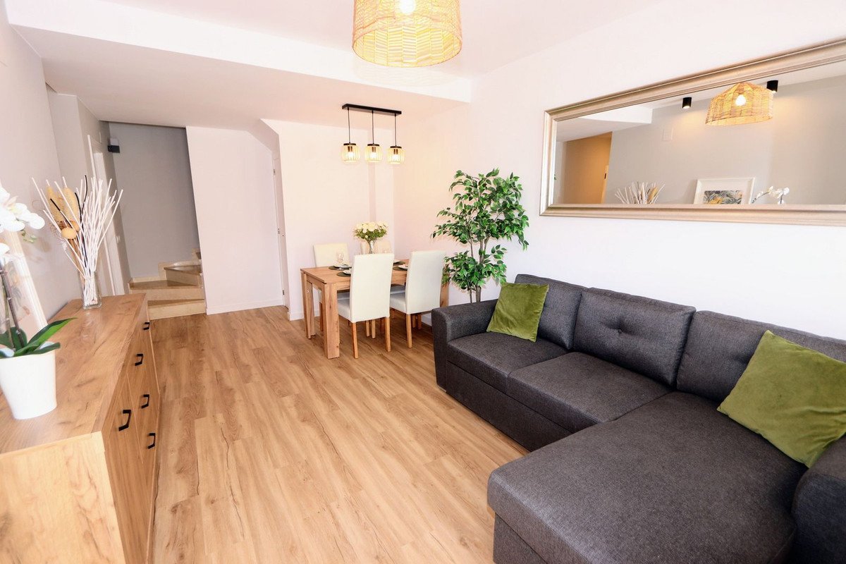 Open-plan living and dining room with gray sofa, wooden floor, and dining table