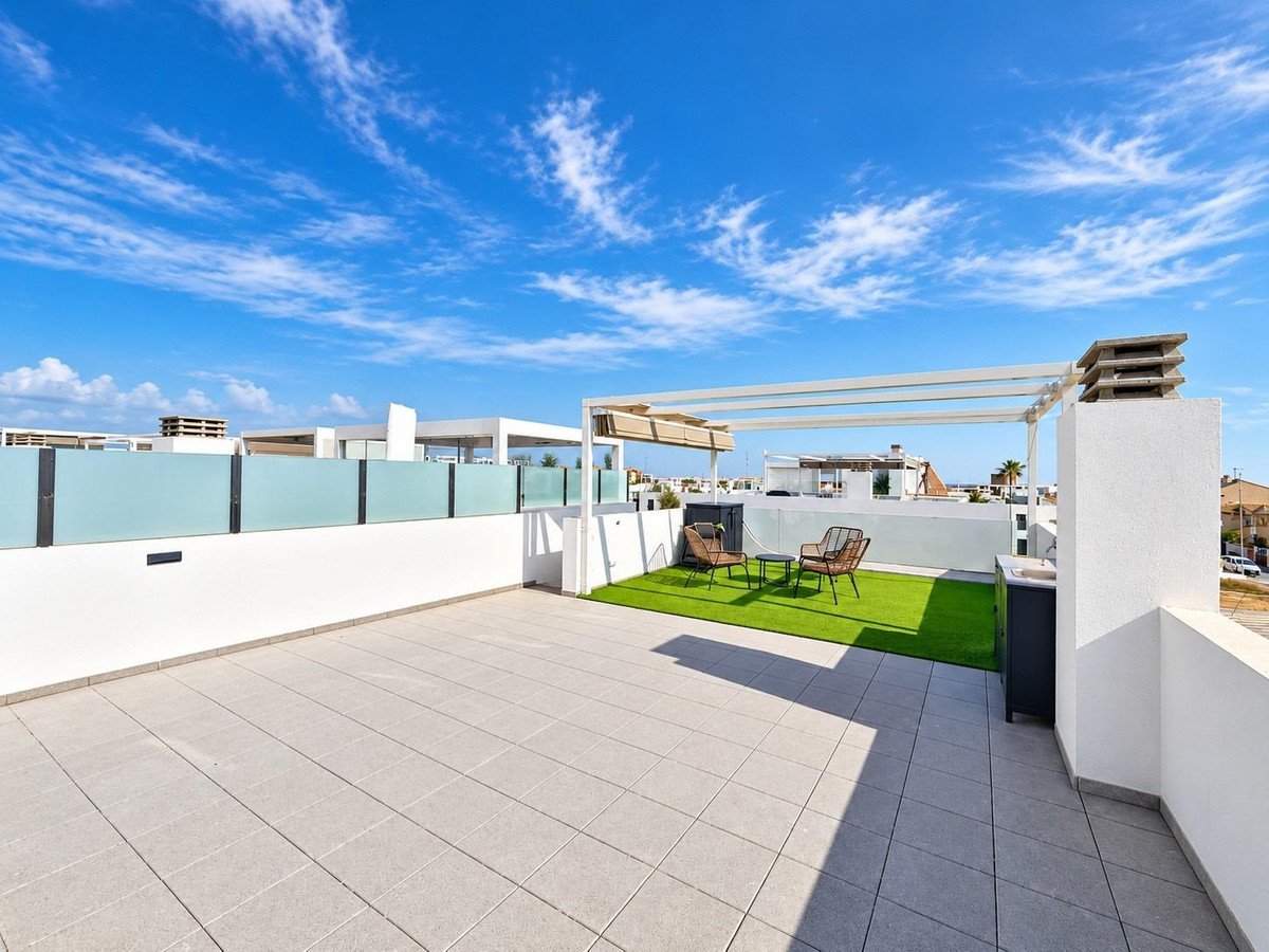 Modern terrace with tiled floor, artificial grass area, seating, and a pergola for outdoor living.