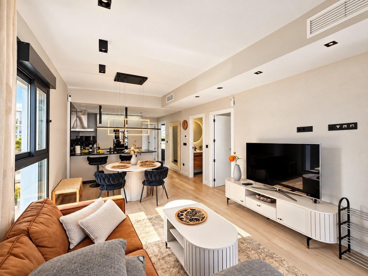 Modern open-plan living, dining, and kitchen area with contemporary furniture and a large TV.
