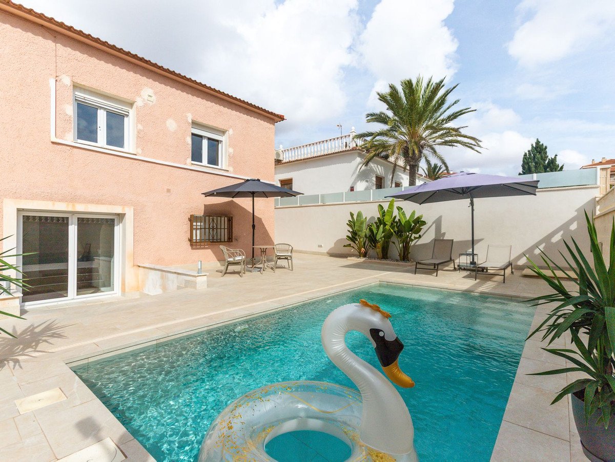 Villa with swimming pool, outdoor seating, palm trees, and a swan float
