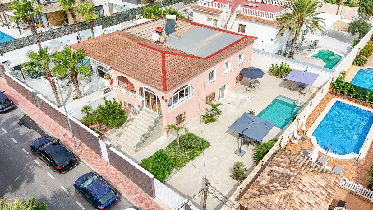 Aerial view of a two-story villa with swimming pools, patio, and palm trees