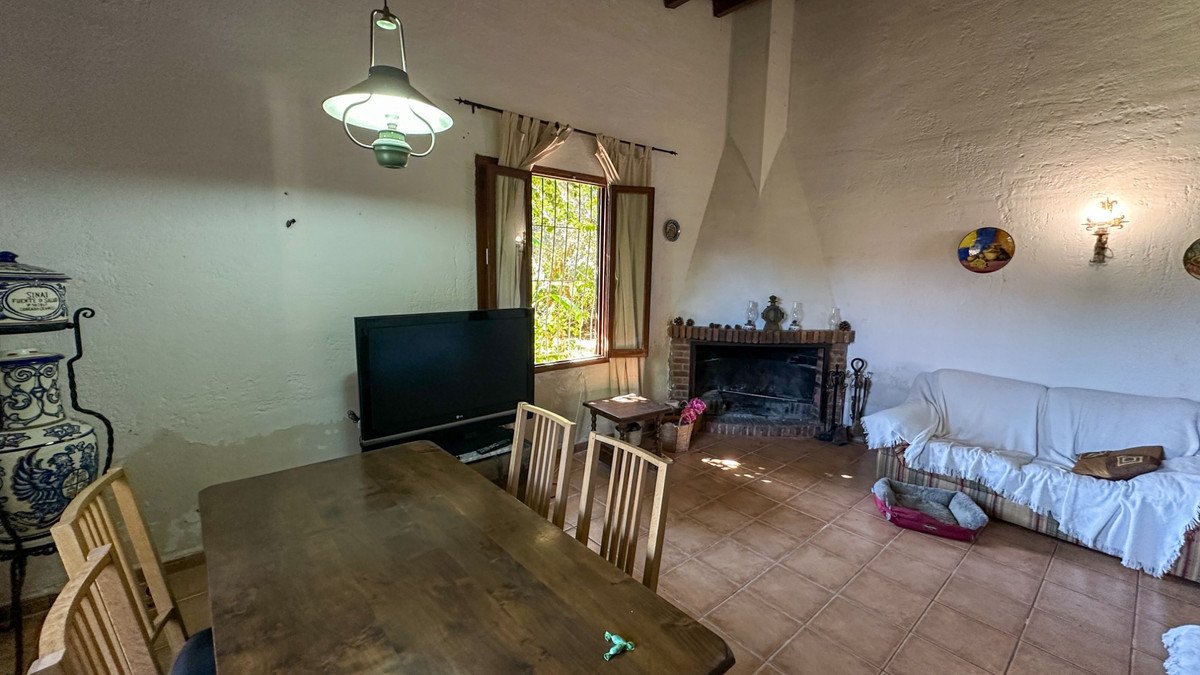 Dining and living room with fireplace, TV, and outdoor view through window