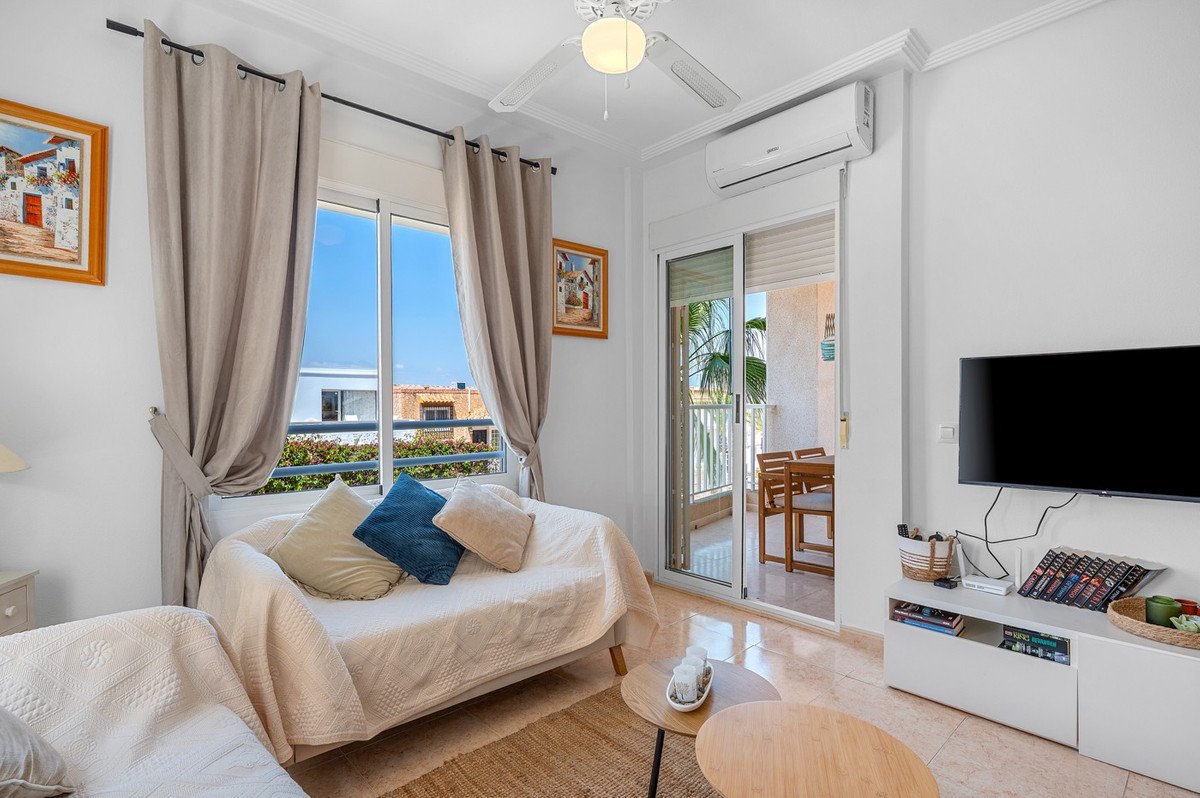 Cozy living room with balcony view, featuring a sofa, TV, and sliding glass doors.