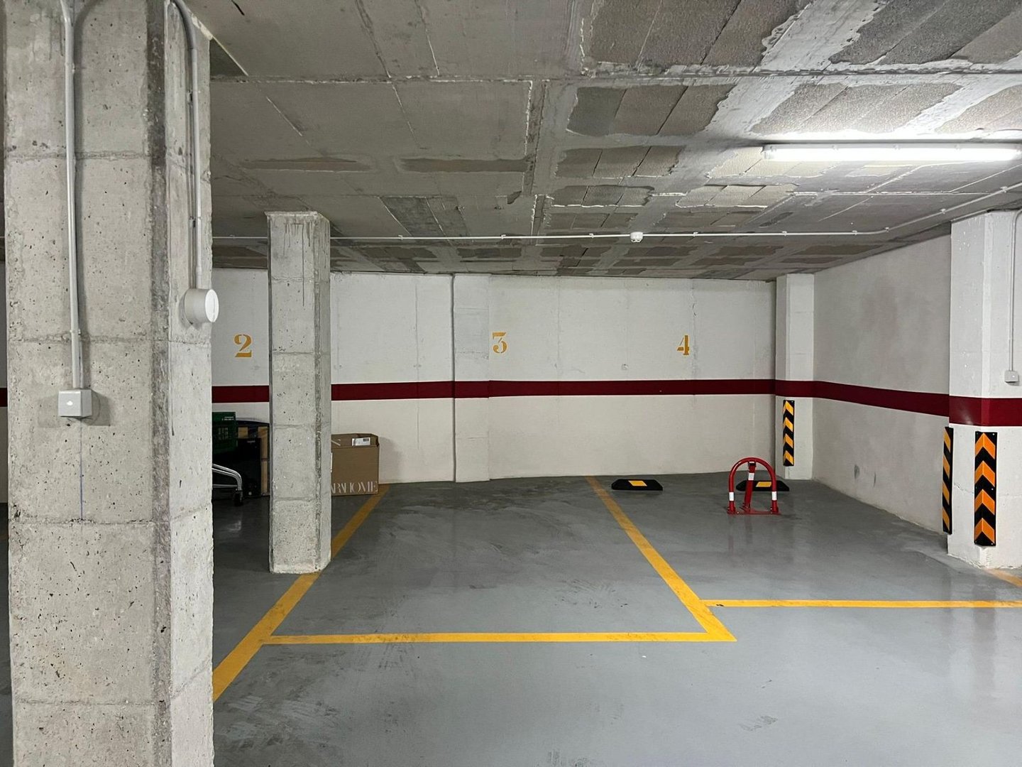 Industriële parkeergarage met genummerde parkeerplaatsen en betonnen pilaren.