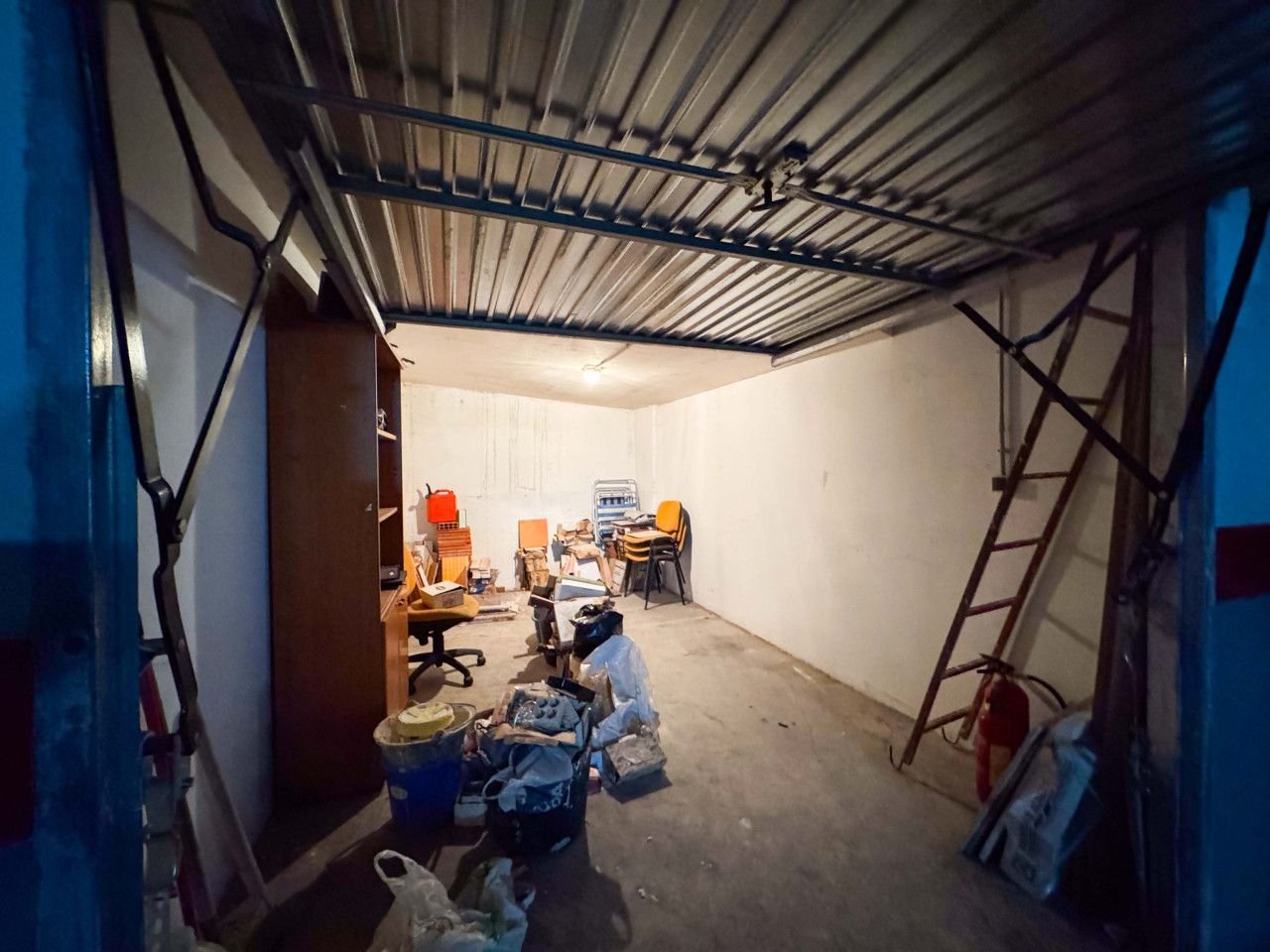 Industrial garage with metal roof, cluttered with tools and equipment.