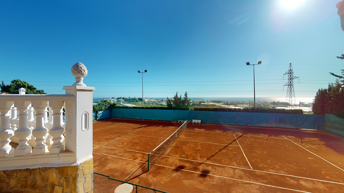 Tennisbaan met uitzicht op de kustlijn vanaf een balkon.