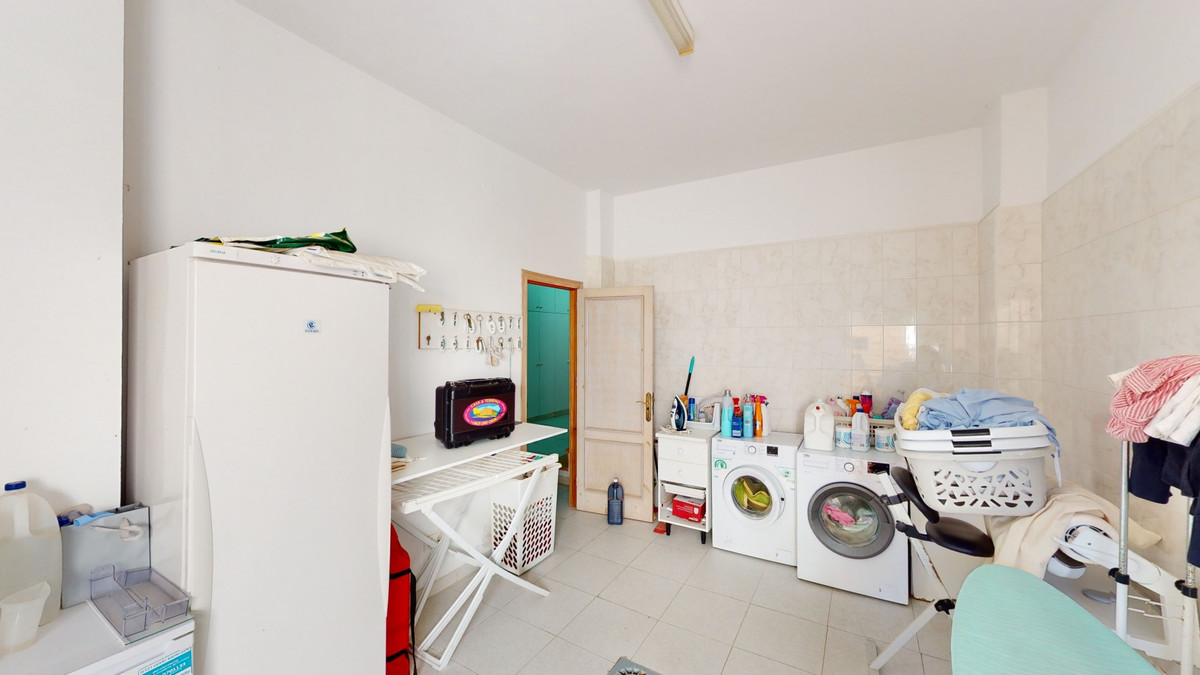 Wasmachine, koelkast en opbergruimte in de wasruimte.