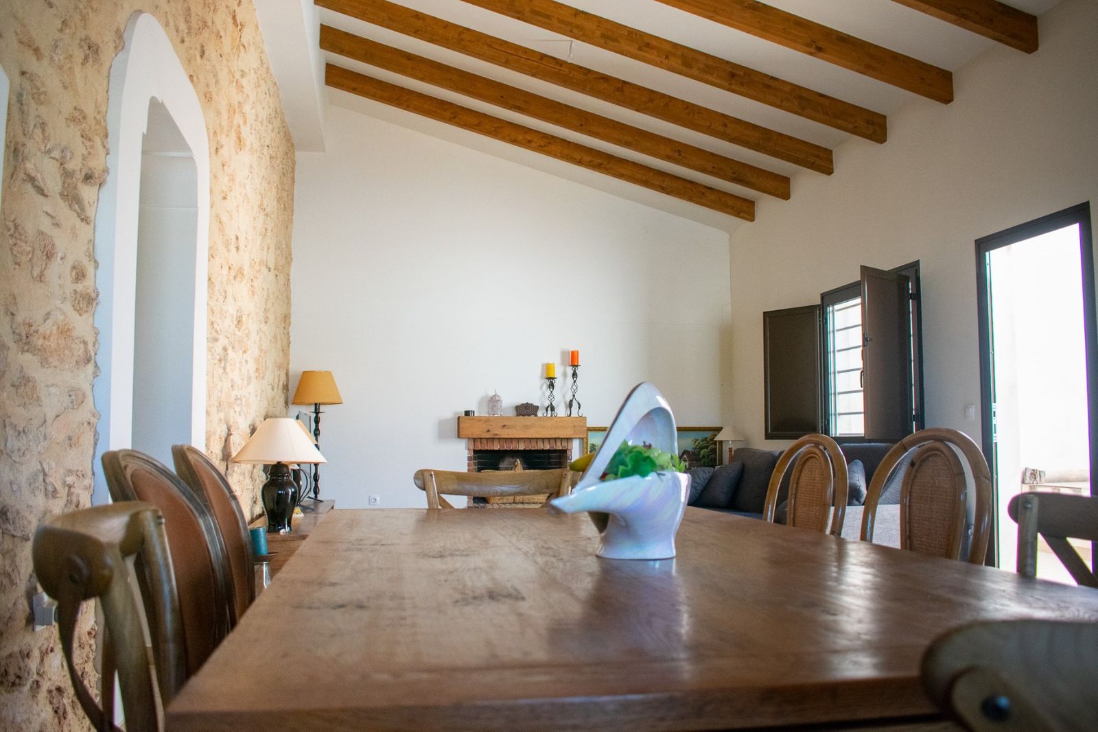 Rustieke eetkamer met houten tafel, balkenplafond en open haard