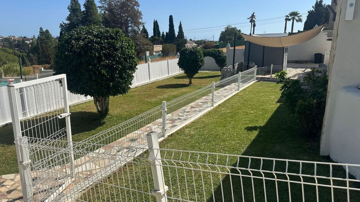 Goed onderhouden tuin met wit hekwerk en betegeld pad.