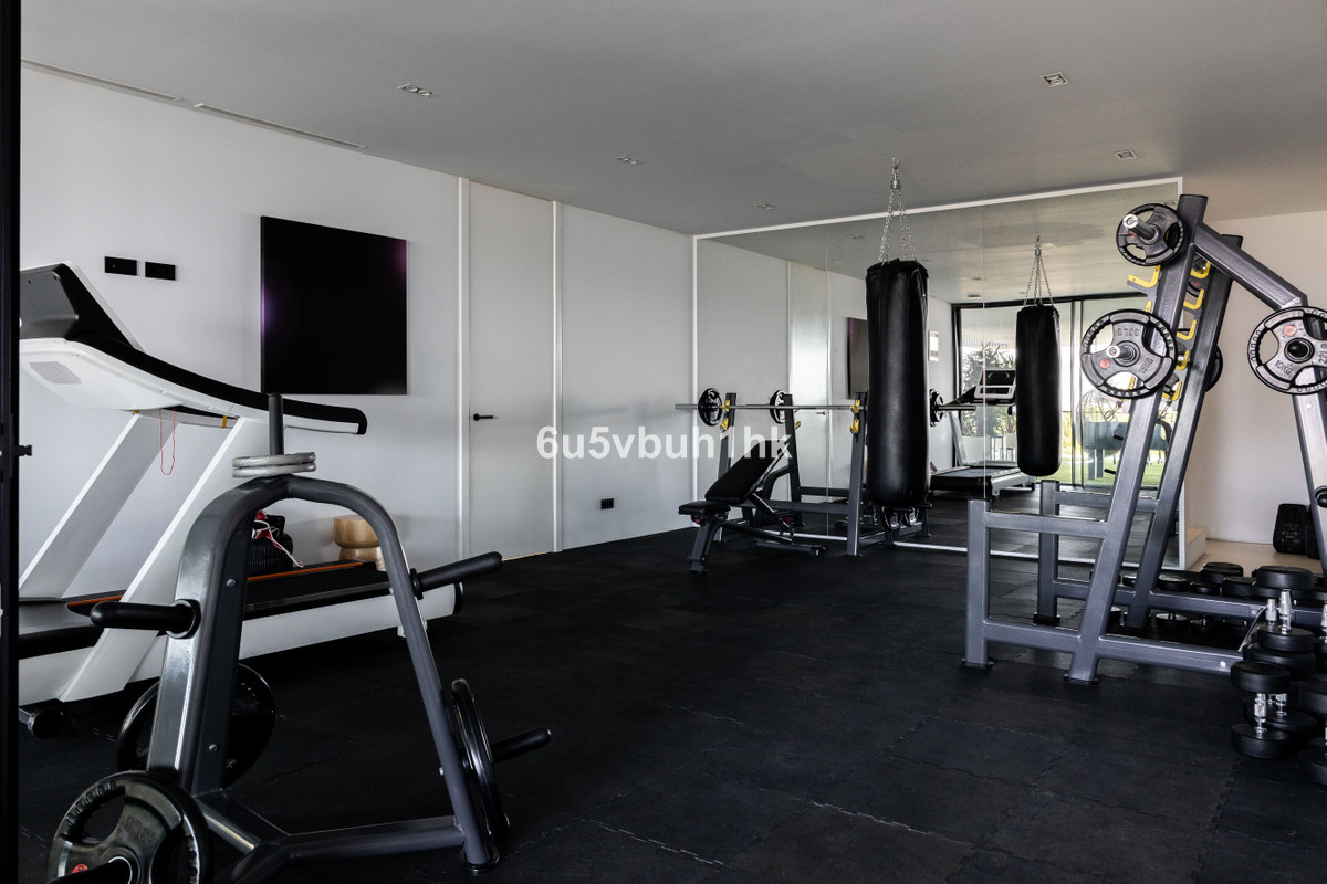 Moderne home gym met diverse fitnessapparatuur zoals een loopband en gewichten.