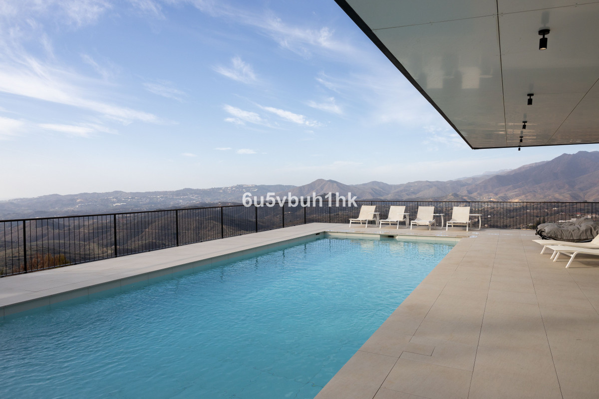 Zwembad met ligstoelen en uitzicht op de bergen.