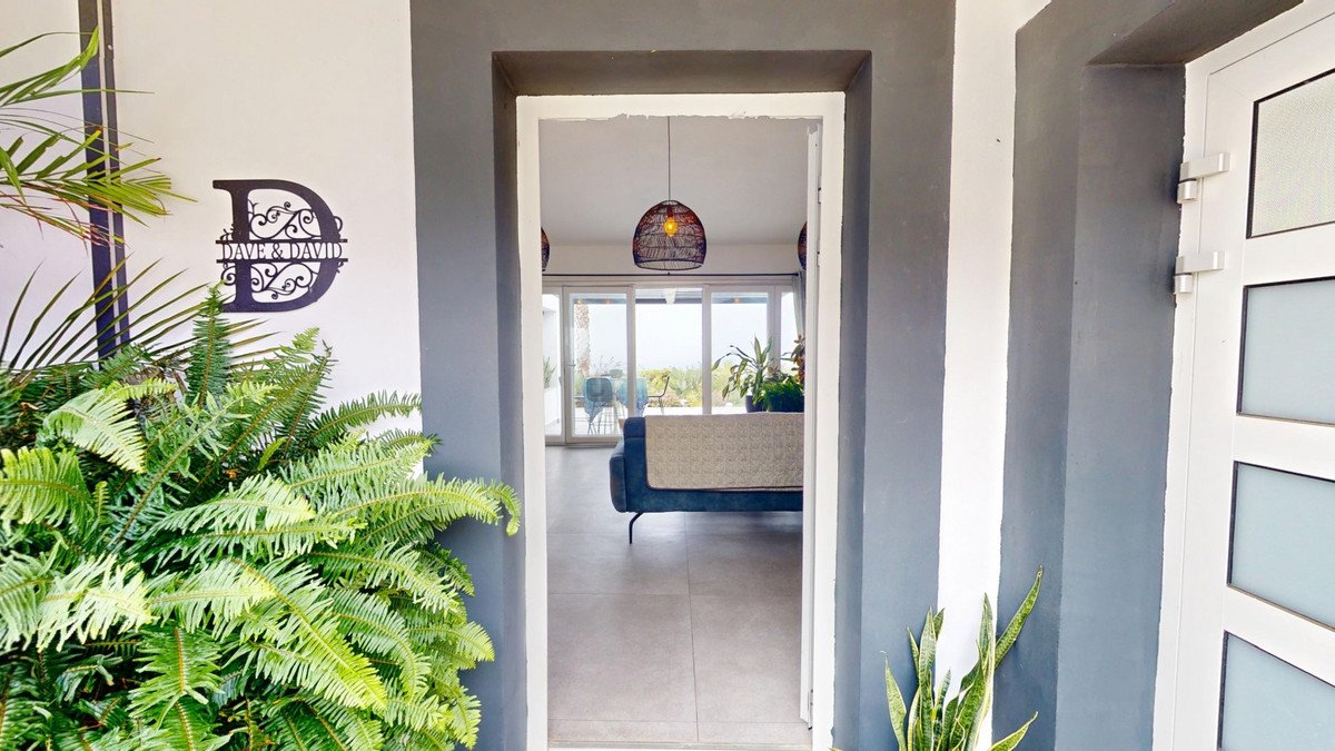 View through an entryway to a living room with a sofa, large sliding glass doors, and an ocean view.