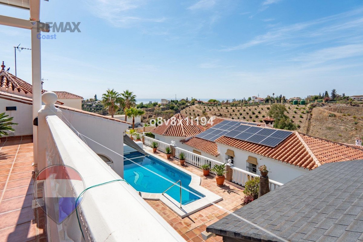 A villa with a swimming pool, solar panels, and a view of the Mediterranean Sea on a sunny day.