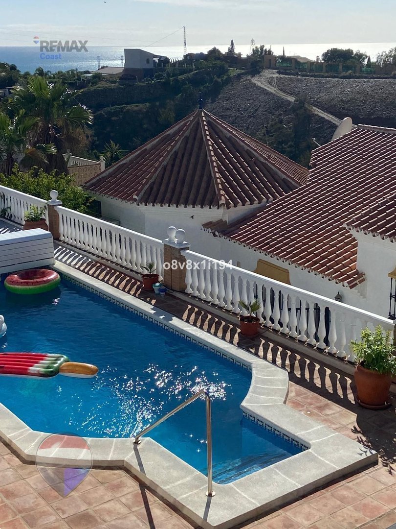 Outdoor swimming pool with inflatable toys and a beautiful view of the sea and surrounding hills.
