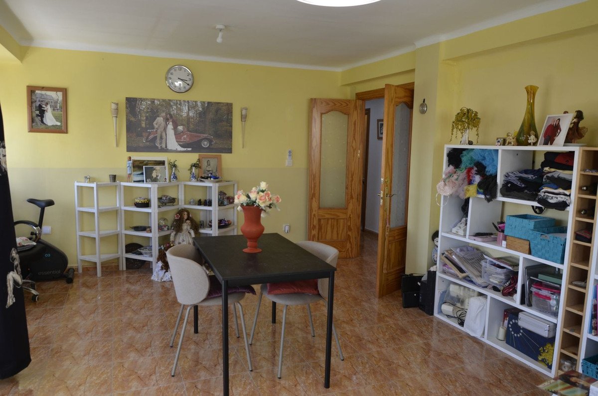 A bright yellow living and dining area with wooden doors, shelving units filled with items, and a dining table.