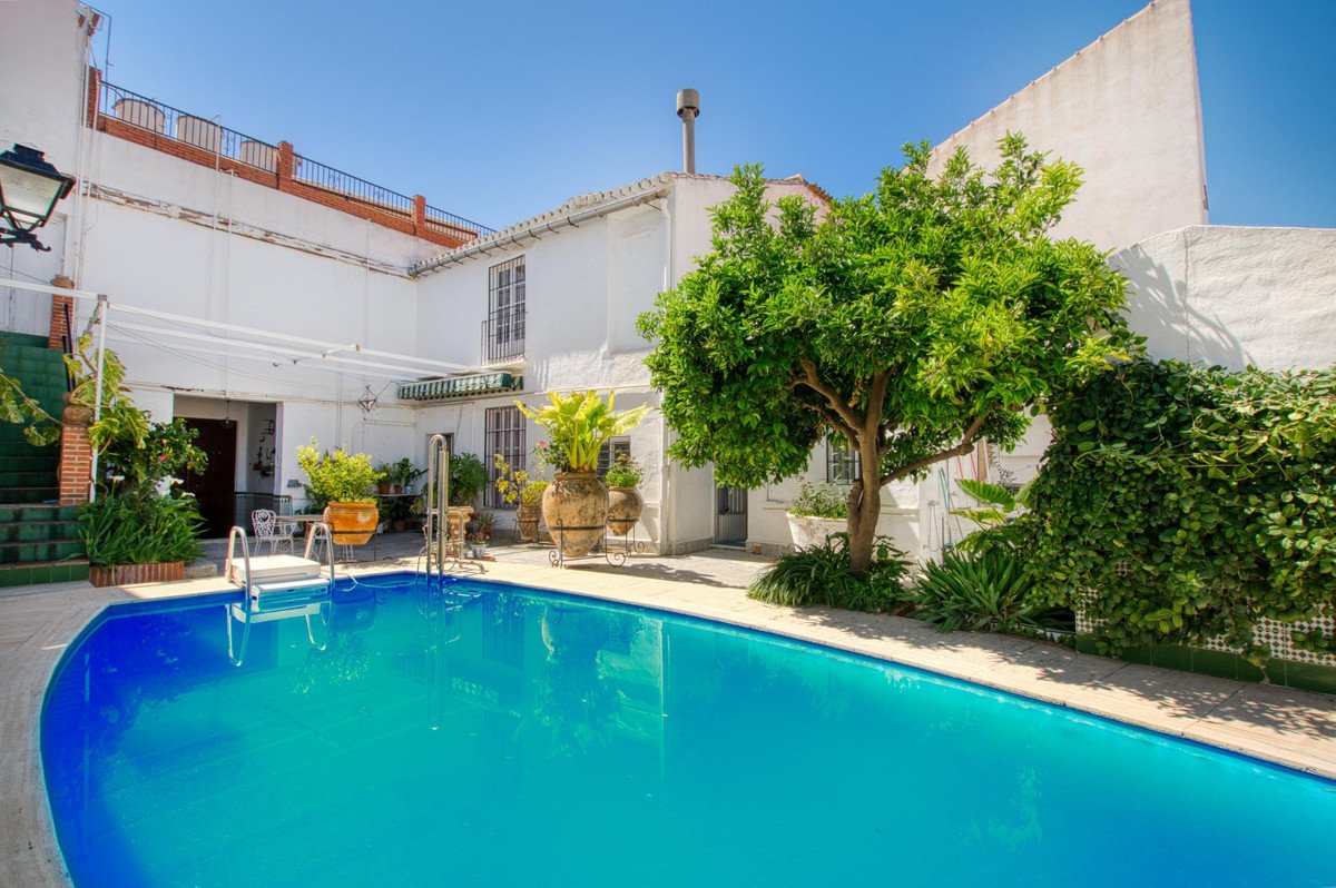 Swimming pool surrounded by white walls and lush green plants