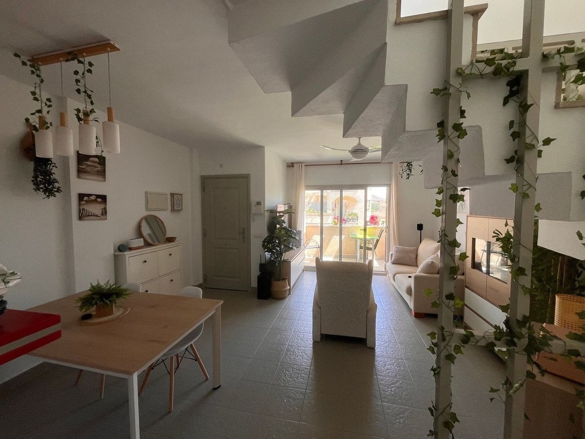 Open-plan living and dining area with staircase, sofa, and sliding glass door to balcony