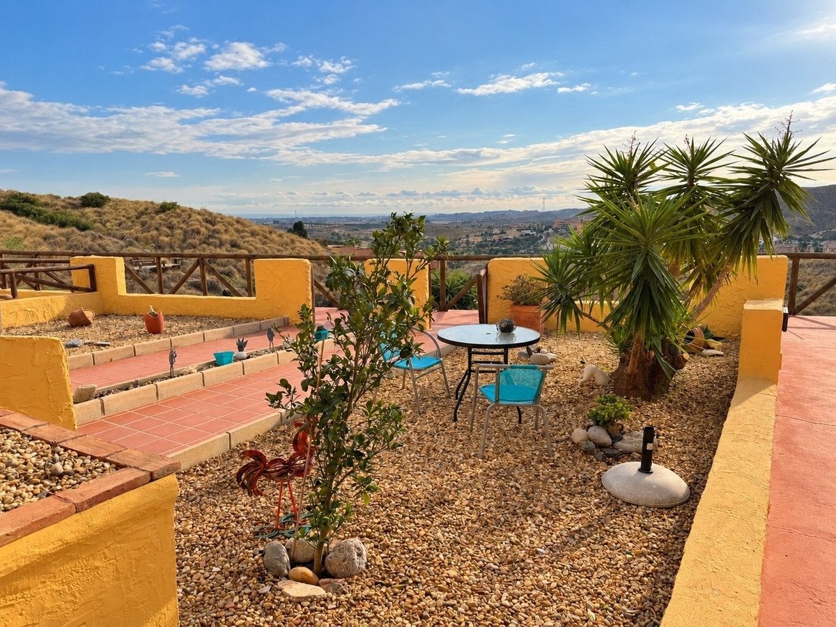 Rooftop terrace with mountain view, gravel garden, blue chairs, and yellow walls