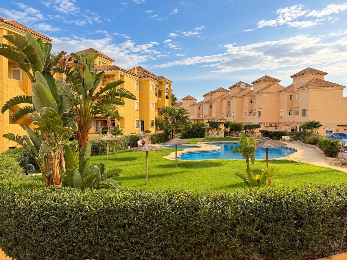 Yellow apartment complex with swimming pool and lush green lawn