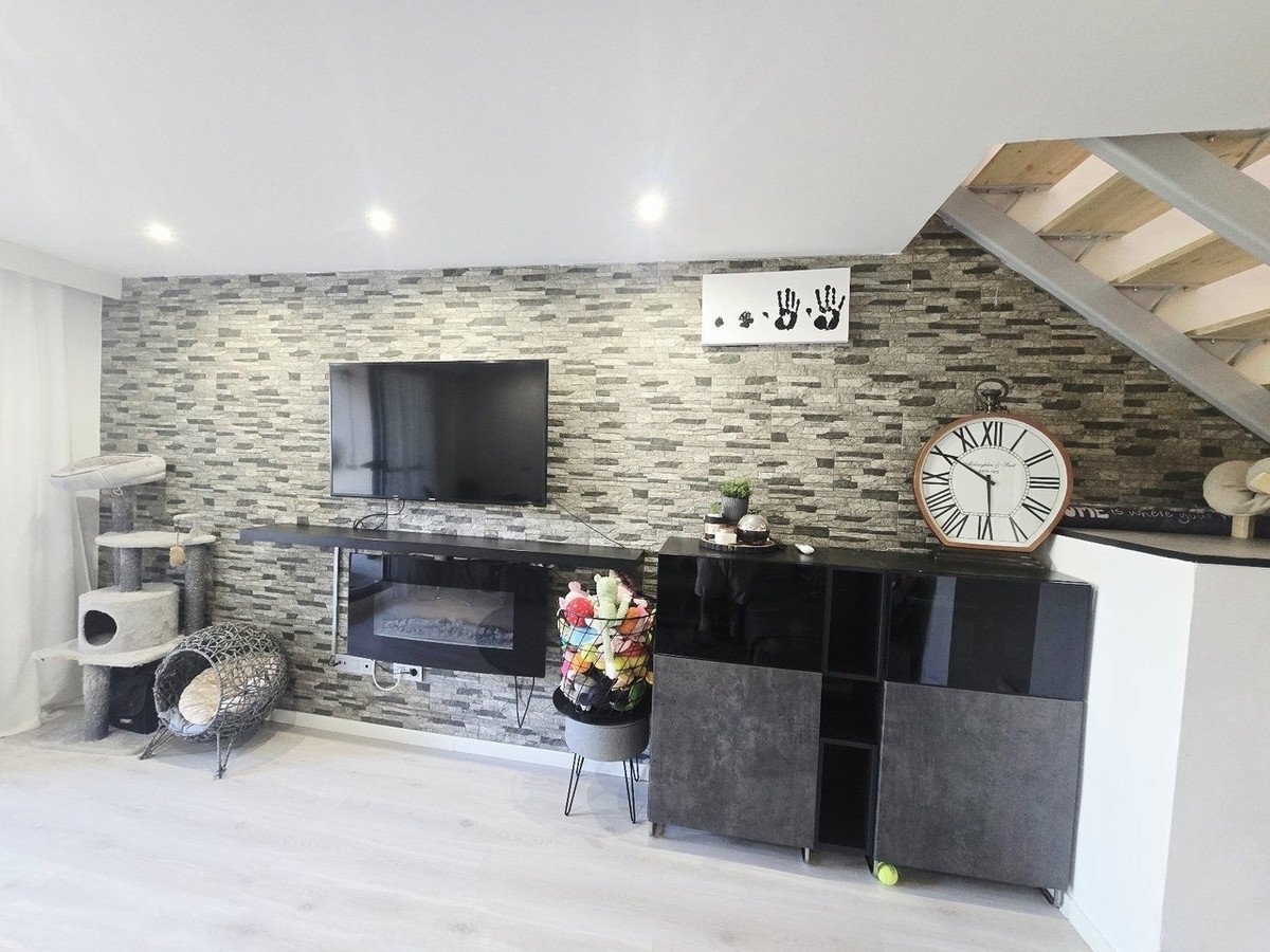 Modern living room with stone accent wall, fireplace, TV, and cat furniture