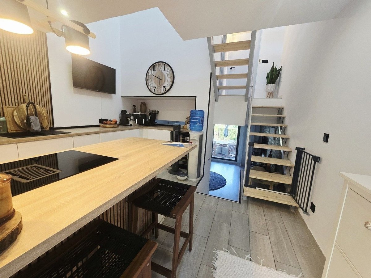 Modern kitchen with open staircase, island, and view to outdoor patio