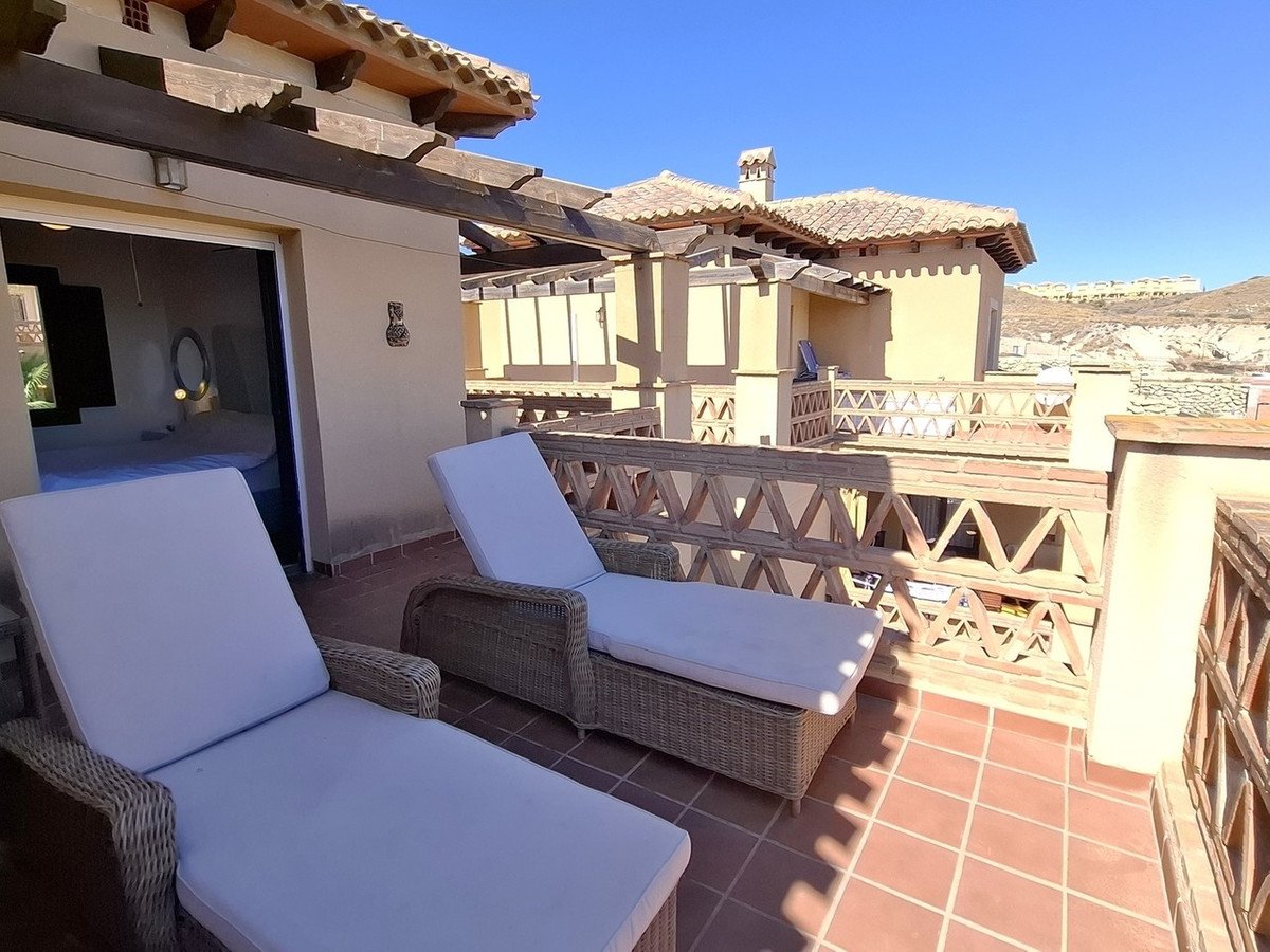 Terrace with two lounge chairs, offering a view of the surrounding buildings and landscape under a clear blue sky.