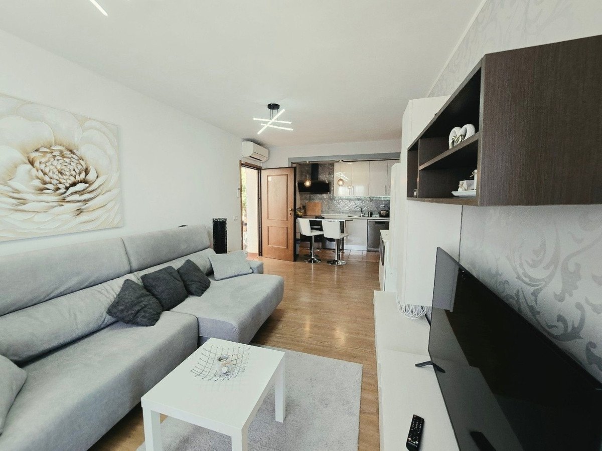 Modern living room with grey sofa, open plan kitchen, and wooden flooring