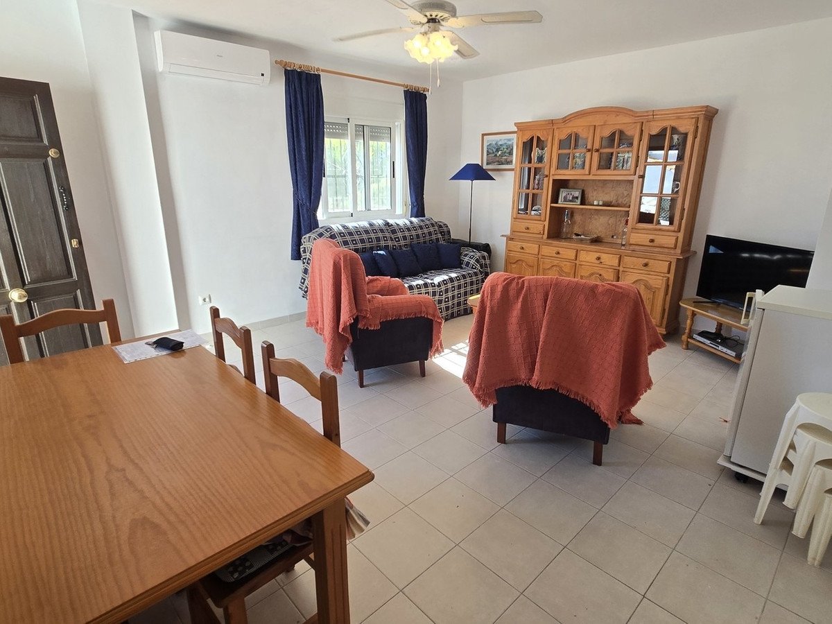 Cozy living and dining area with patterned sofa, armchairs, wooden hutch, and dining table.