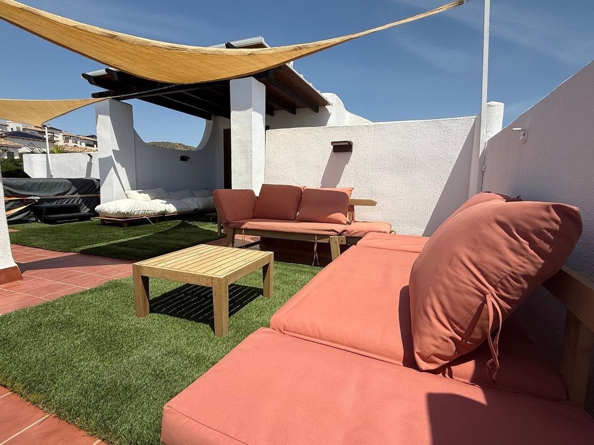 Outdoor terrace with sun shade, seating, and artificial grass under clear sky