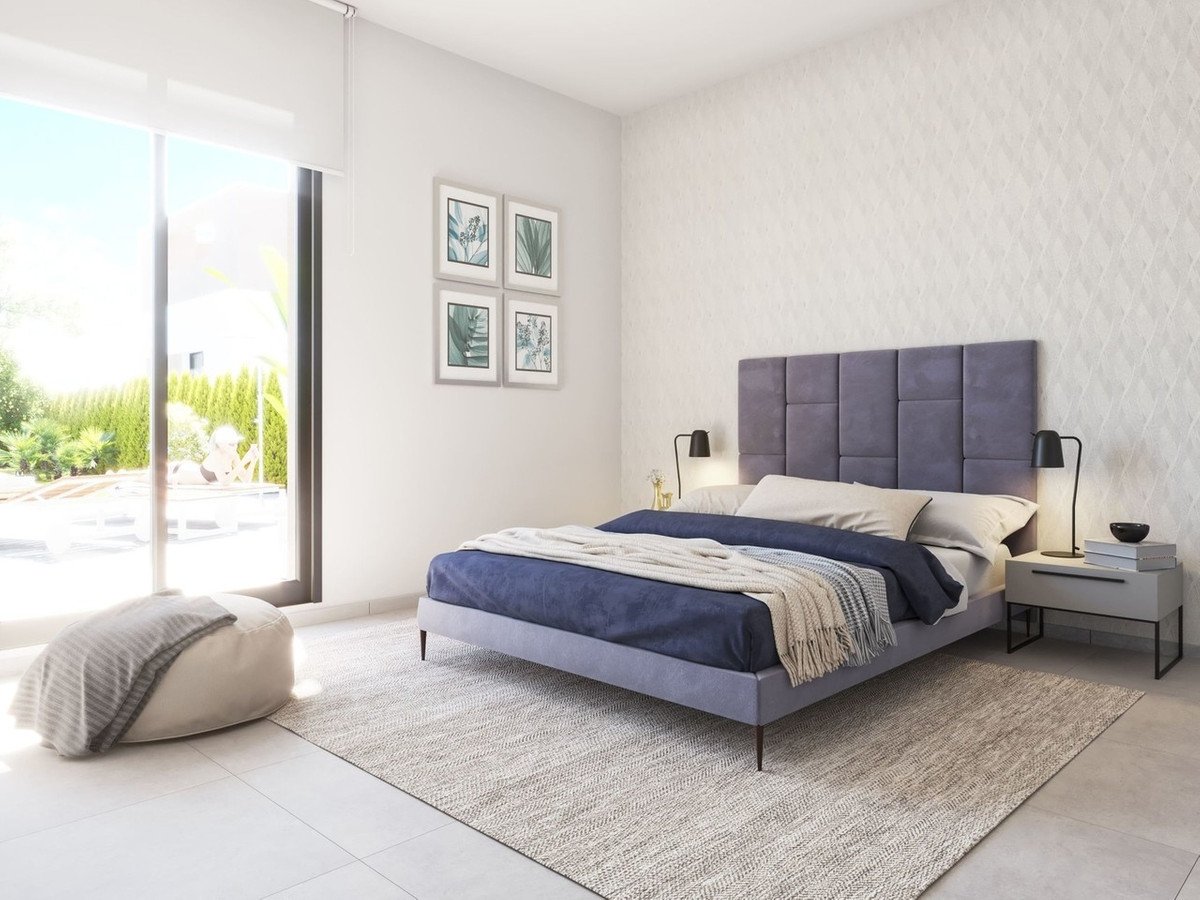 A modern bedroom with a large bed, bedside tables, and a sliding glass door leading to a pool area and garden.