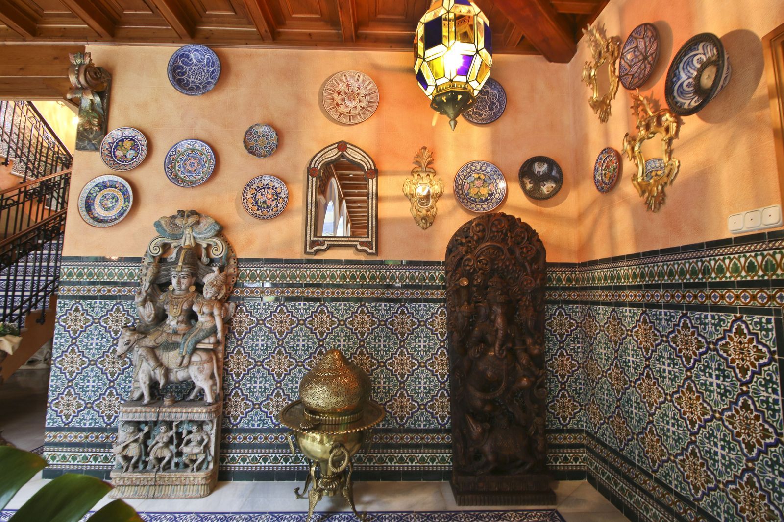 Eclectisch interieur met culturele kunst, decoratieve borden en een Marokkaanse lamp.