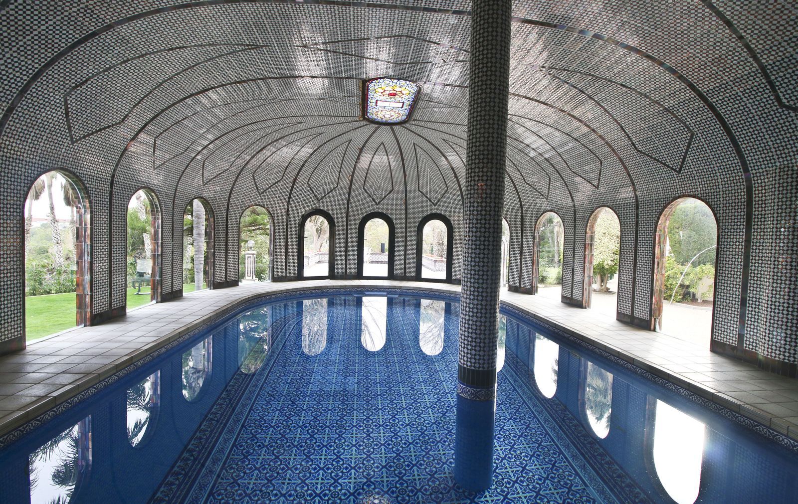 Overdekt zwembad in villa met mozaïekkoepel en reflecties.