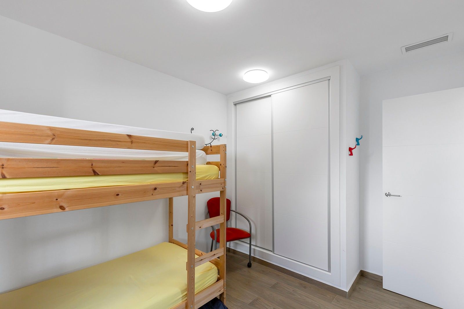 Slaapkamer met houten stapelbed en witte kledingkast