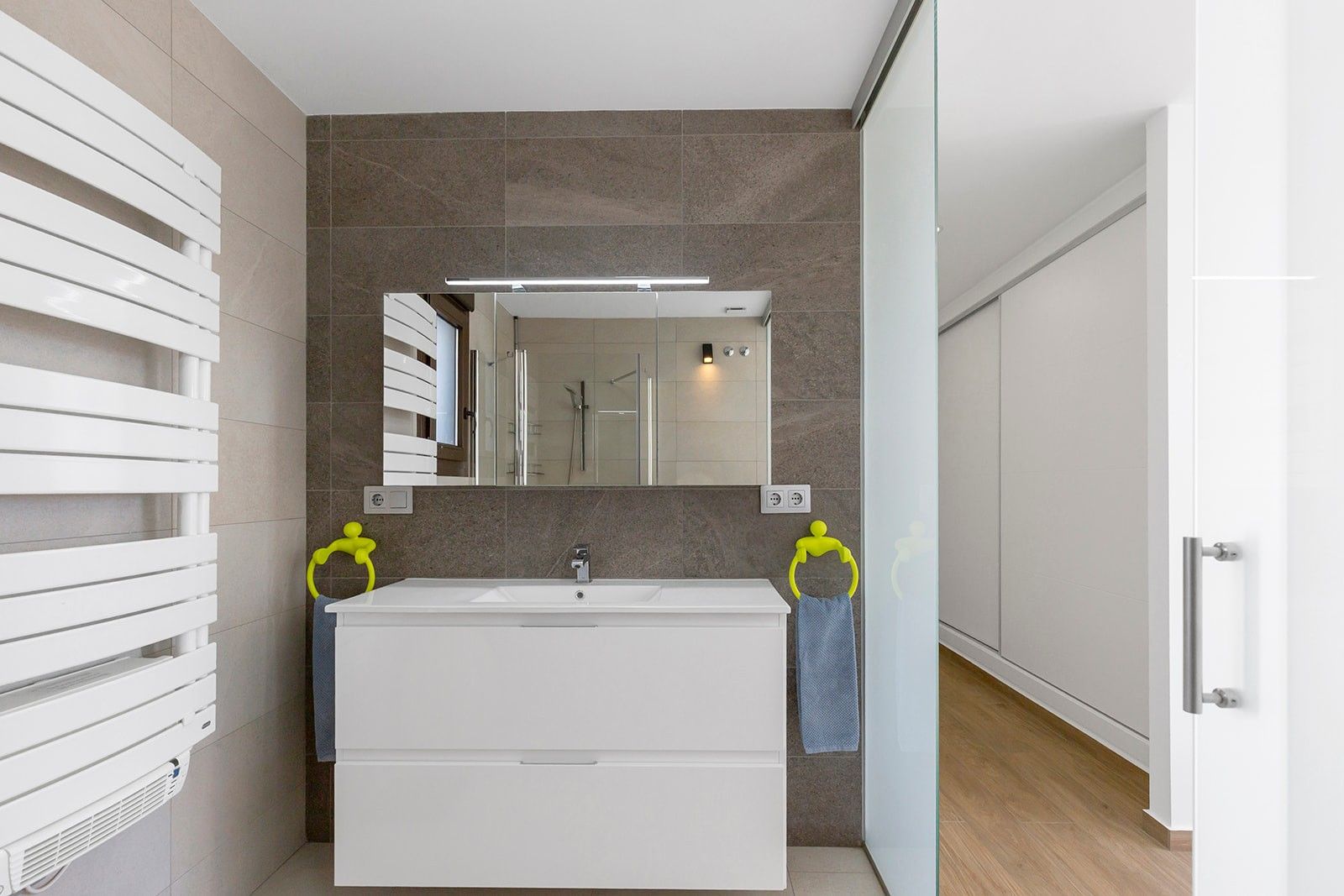 Moderne badkamer met witte wastafel, spiegel en handdoekradiator