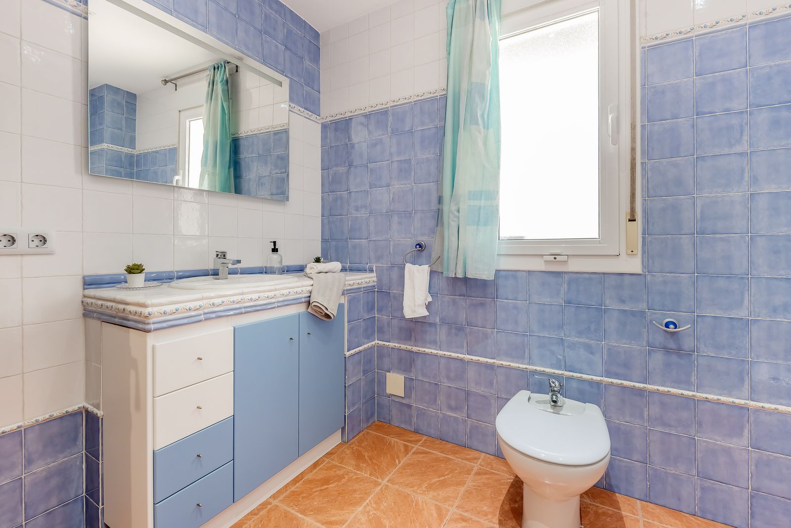 Badkamer met blauwe tegels, wastafel en bidet.