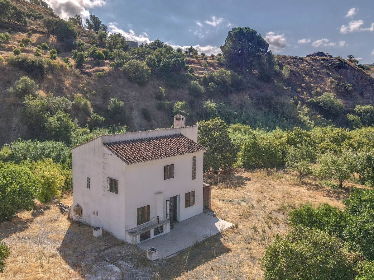 Buitenkant van een landhuis met terras en heuvelachtige achtergrond.