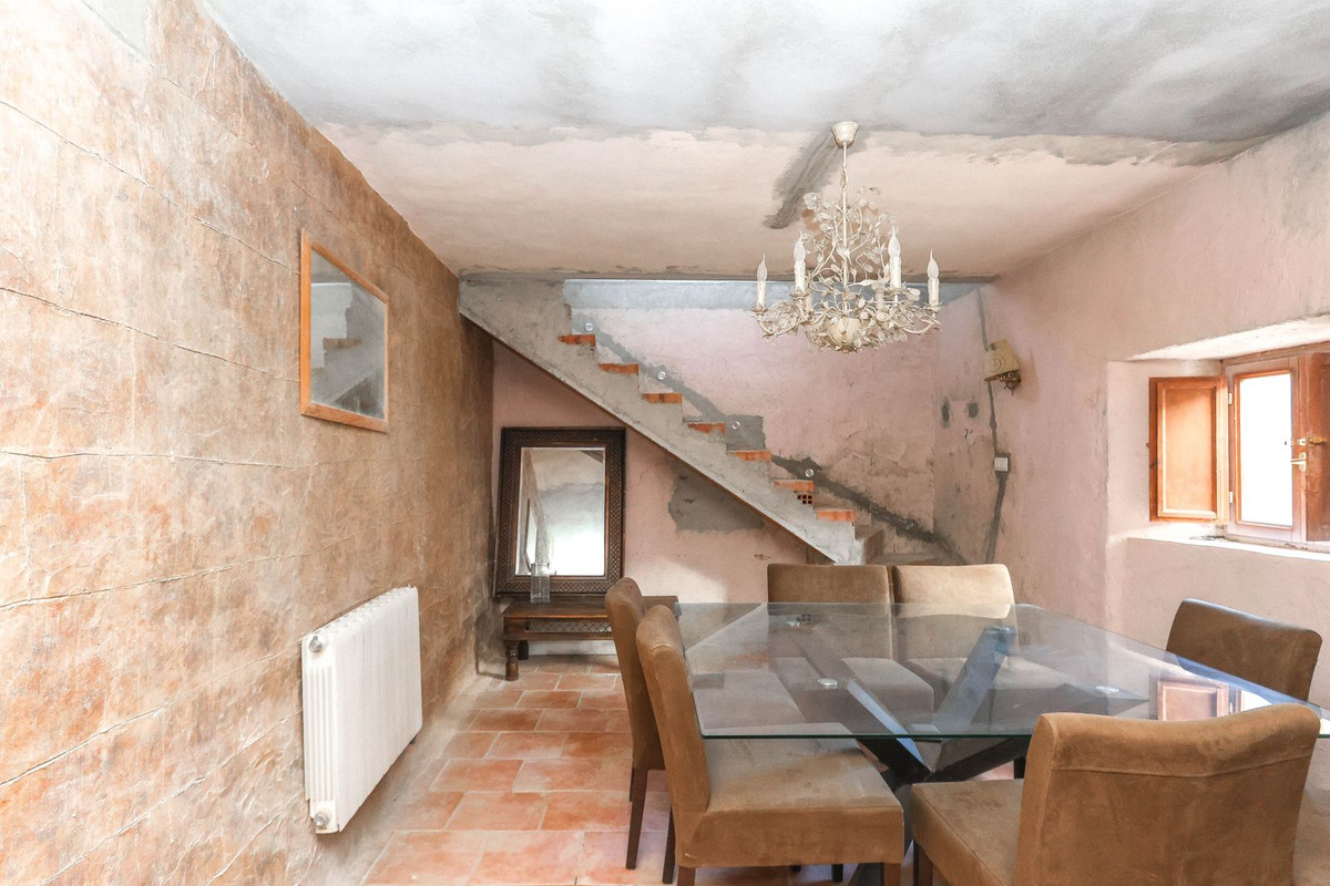 Eetkamer met rustieke trap, glazen tafel en bruine stoelen.